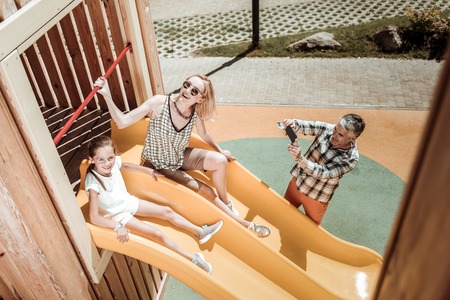 Joyful moments. Happy positive man holding his smartphone while taking photos of his familyの写真素材