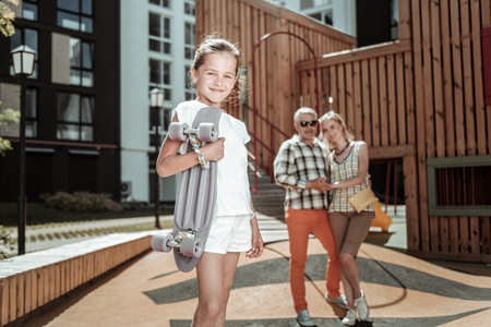 My hobby. Delighted cute girl holding a skateboard while having fun outdoorsの写真素材