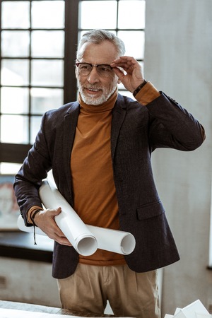 Holding map papers. Grey-haired interior designer holding map papers with plans for the apartmentの写真素材