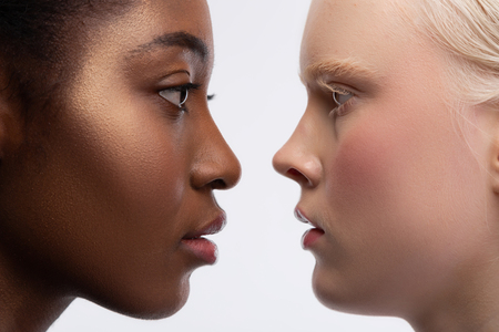 Looking into eyes. Two young multinational women with different skin color looking into eyes of each otherの写真素材