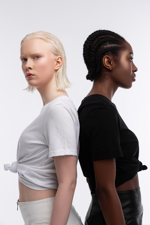 Skirts and t-shirts. Models wearing white and black skirts and t-shirts standing back to back while posing in photo shootの写真素材