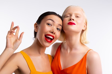 Looking funny. Dark-haired woman looking really funny while spending time with blonde friend