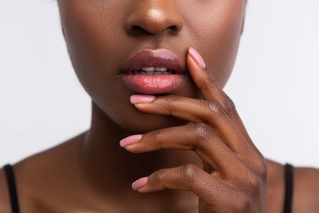 Shiny lip gloss. Close up of young African-American woman touching lips with shiny lip glossの写真素材