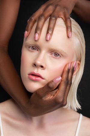Touching woman. African-American young appealing woman touching face of woman with white skinの写真素材