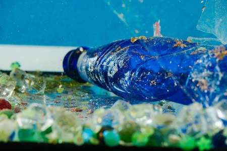 Transparent ruined plastic. Dirty blue crumpled bottle being covered with dust and rust and lying in trashの写真素材