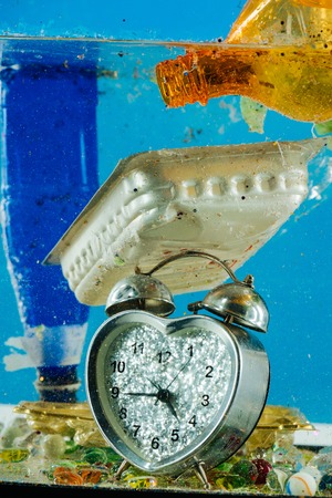 Sequins flying around. Thrown silver heard shaped clock placed on the bottom with plastic garbage and used containersの写真素材