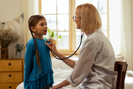 To see a doctor. A sweet pretty small girl with long braids breathing out while a short-haired...