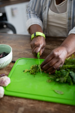 Be careful. Close up of female that cutting greenery, being alone in the kitchenの写真素材