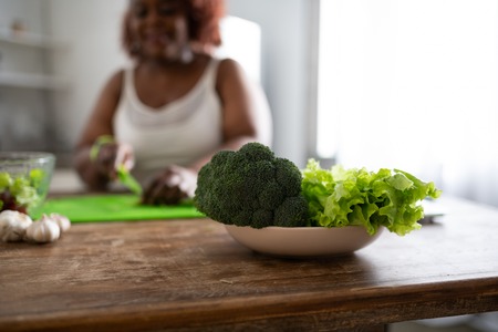 Morning routine. Close up of bowl that standing on the table, fresh broccoli and salad being ready for eatingの写真素材