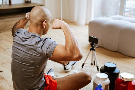 T-shirt and shorts. Young bald bodybuilder wearing grey t-shirt and red shorts showing bicepsの写真素材
