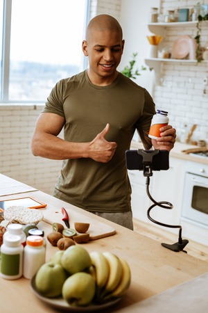 Blog about food. Strong sportsman feeling good while filming blog about food and supplementsの写真素材