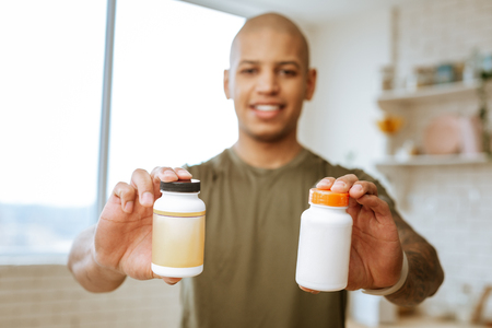 Vitamins in hands. Close up of two packs of vitamins in hands of professional young sportsmanの写真素材