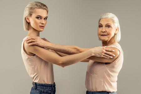 Special photoshoot. Nice serious women standing against grey background while posing for a photoの写真素材