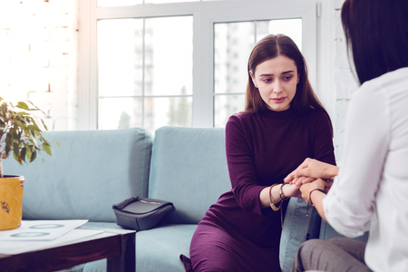 Lady visiting psychologist. Crying depressed upset attractive young lady being comforted during a visit to a psychologistの写真素材