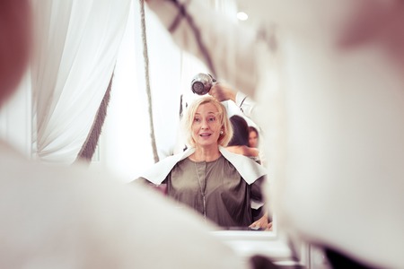 Delighted woman expressing positivity while enjoying her hairstyleの写真素材
