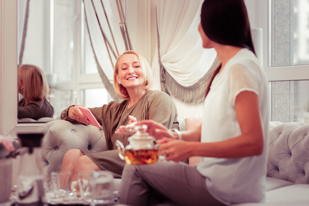 Relaxed atmosphere. Amazing blonde woman expressing positivity while talking to her friendの写真素材