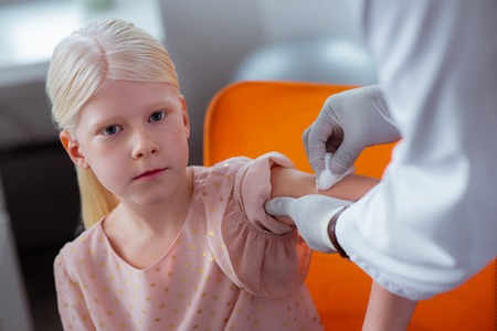 Girl feeling calm. Beautiful blonde-haired schoolgirl feeling calm while getting injectionの写真素材