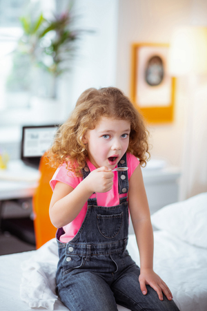 Hospital and syrup. Stylish little beautiful and cute girl sitting in the hospital and taking cough syrupの写真素材