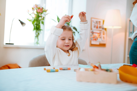 White sweater. Funny little girl wearing white sweater playing with threads visiting mom in atelierの写真素材