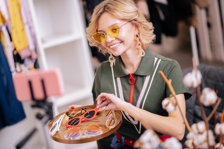 Trends of summer. Beaming beautiful stylist feeling excited while filming blog about trends of...