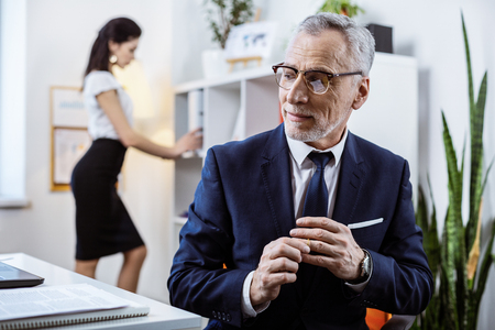 Grey-haired pleased workmate. Tricky senior woman taking off wedding ring while enjoying body of younger beautiful ladyの写真素材