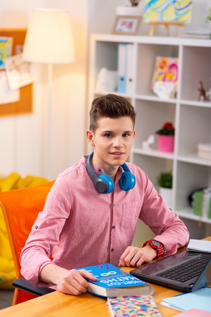 Homework time. Handsome dark-haired teenager sitting at the table studying and doing homeworkの写真素材