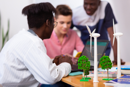 Windmills near students. Models of windmills standing on table near three smart students having brainstormingの写真素材