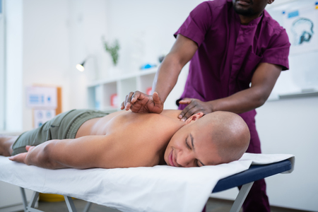 Truly enjoying massage. Bald man truly enjoying massage while visiting massage therapist at the weekendの写真素材