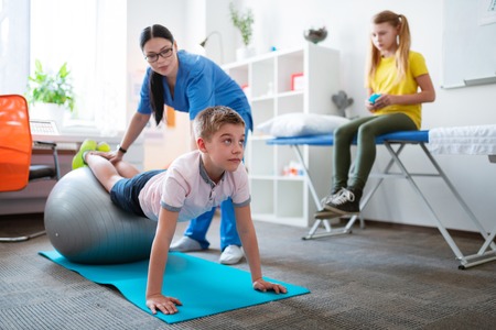 Hard-working little boy. Diligent short-haired boy training with special equipment while having...