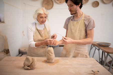 Favourite activity. Serious creative man and woman standing together while making potsの写真素材