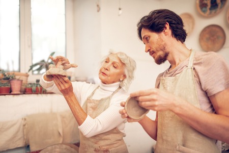 Special design. Serious creative woman creative a clay bowl while working in the workshopの写真素材