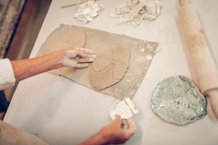Beautiful artwork. Top view of a clay piece with special ornament lying on the tableの写真素材