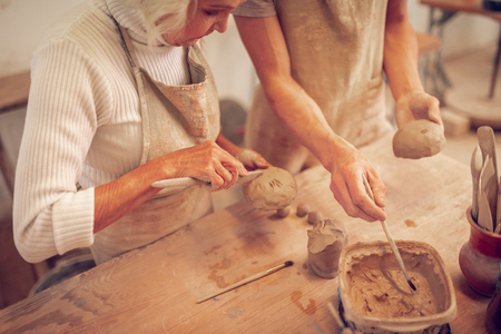 Focusing on process. Tip view of a serious concentrated aged woman focusing on pot making processの写真素材
