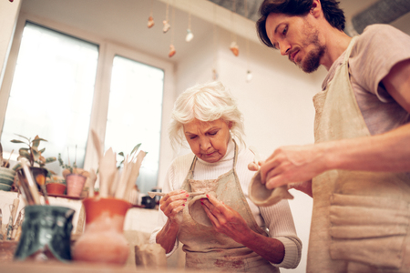 Careful process. Low angle of a pleasant serious woman looking at her bowlの写真素材