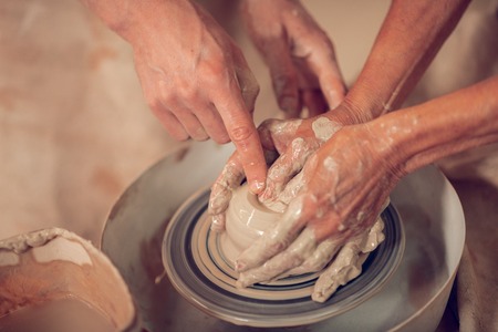 Special art. Top view of artists hands on the pottery wheel while making pots