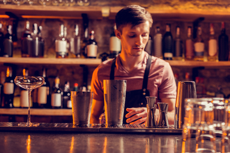 Dark-haired bartender. Busy dark-haired bartender wearing uniform making cocktail while working at nightの写真素材