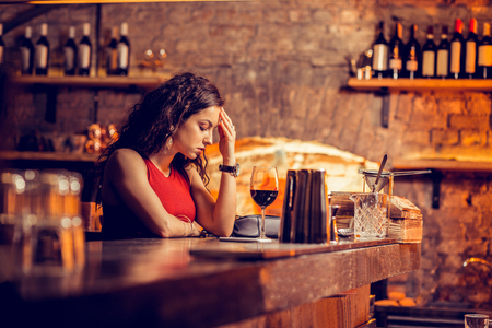 Woman having headache. Dark-haired woman having headache while waiting for man in the barの写真素材