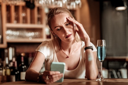 Deep in thoughts. Attentive female person sitting in bar and waiting for her boyfriendの写真素材