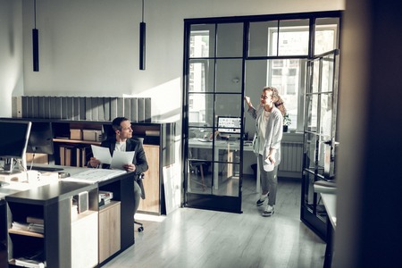 Trainee and busy. Young trainee coming to her busy boss having some important questionsの写真素材