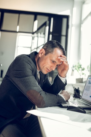 Touching his head. Mature successful businessman touching his head while feeling busy of workの写真素材