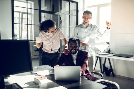 Supporting boss. Staff of the company supporting their dark-skinned boss after successful dealの写真素材