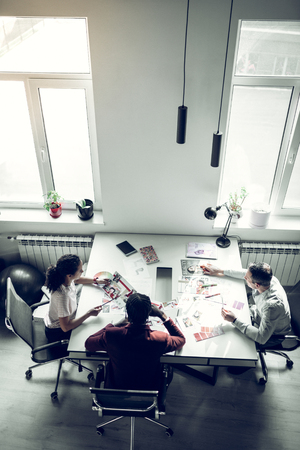 Having discussion. Top view of magazine staff sitting at the table and having discussion about new issueの写真素材