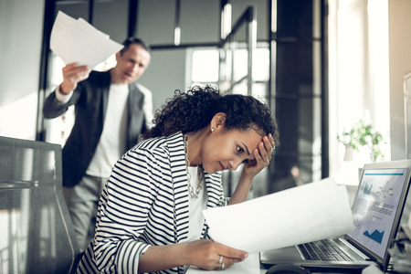 Employee feeling guilty. Dark-eyed employee feeling guilty for not completing the task while...