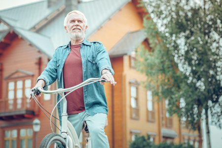 My hobby. Nice bearded man being in front of his house while riding a bicycleの写真素材