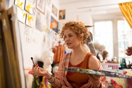 Artist feeling emotional. Curly red-haired artist feeling emotional while painting in workshopの写真素材