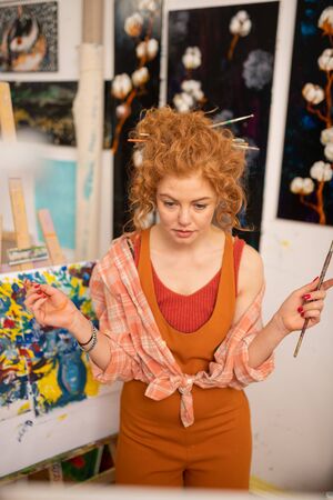Some hesitations. Curly red-haired artist having some hesitations while choosing colorの写真素材
