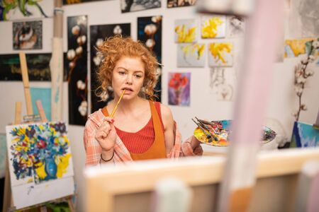 Red-haired art student. Red-haired art student feeling involved in making home task for university