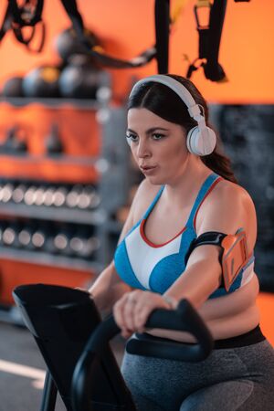 Woman hardly breathing. Dark-haired overweight woman hardly breathing while cycling for too long in...