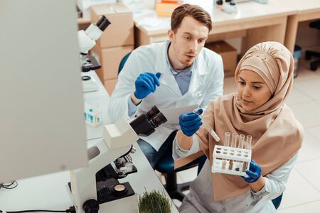 Samples for research. Smart muslim woman looking at test tubes while choosing samples for the researchの写真素材