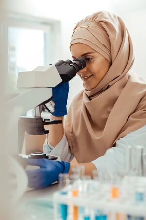 Innovative results. Happy cheerful woman smiling while doing a successful researchの写真素材